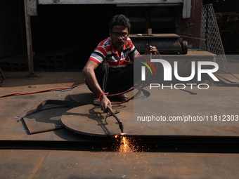 A laborer cuts an iron plate outside a shop at a steel and iron wholesale market in Kolkata, India, on November 26, 2024. In November 2024,...