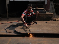 A laborer cuts an iron plate outside a shop at a steel and iron wholesale market in Kolkata, India, on November 26, 2024. In November 2024,...