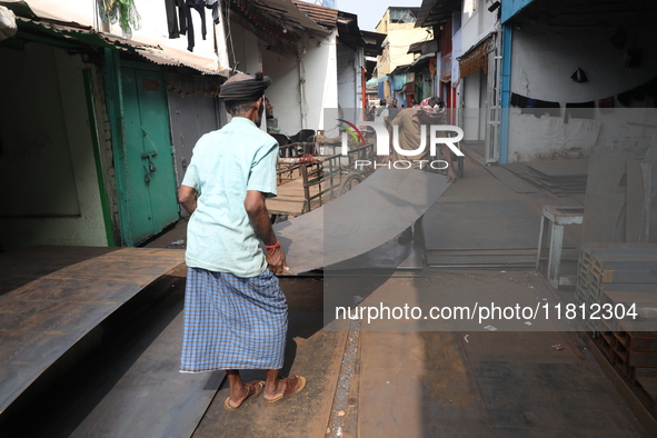 Labourers carry an iron plate outside a shop at a steel and iron wholesale market in Kolkata, India, on November 26, 2024. In November 2024,...