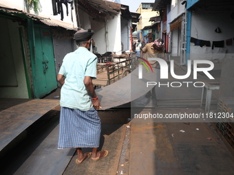 Labourers carry an iron plate outside a shop at a steel and iron wholesale market in Kolkata, India, on November 26, 2024. In November 2024,...