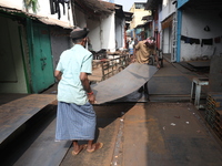 Labourers carry an iron plate outside a shop at a steel and iron wholesale market in Kolkata, India, on November 26, 2024. In November 2024,...