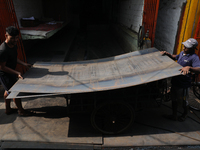 Labourers carry an iron plate to load onto a cycle rickshaw outside a shop at a steel and iron wholesale market in Kolkata, India, on Novemb...