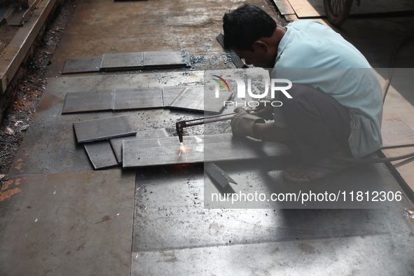 A laborer cuts an iron plate outside a shop at a steel and iron wholesale market in Kolkata, India, on November 26, 2024. In November 2024,...