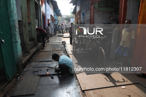 A laborer cuts an iron plate outside a shop at a steel and iron wholesale market in Kolkata, India, on November 26, 2024. In November 2024,...