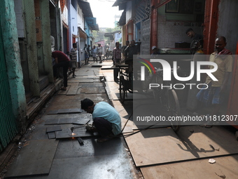 A laborer cuts an iron plate outside a shop at a steel and iron wholesale market in Kolkata, India, on November 26, 2024. In November 2024,...