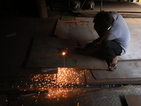 A laborer cuts an iron plate outside a shop at a steel and iron wholesale market in Kolkata, India, on November 26, 2024. In November 2024,...