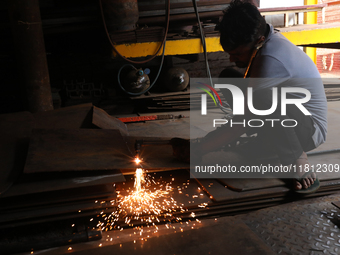 A laborer cuts an iron plate outside a shop at a steel and iron wholesale market in Kolkata, India, on November 26, 2024. In November 2024,...