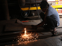 A laborer cuts an iron plate outside a shop at a steel and iron wholesale market in Kolkata, India, on November 26, 2024. In November 2024,...