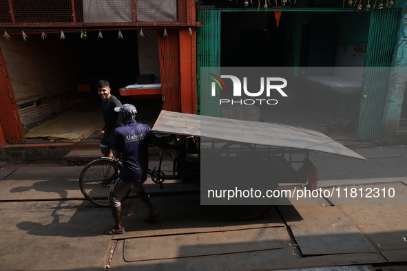 Labourers pull a cycle rickshaw loaded with iron plates at a wholesale iron market in Kolkata, India, on November 26, 2024. In November 2024...