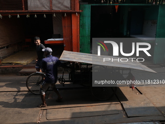 Labourers pull a cycle rickshaw loaded with iron plates at a wholesale iron market in Kolkata, India, on November 26, 2024. In November 2024...