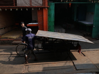 Labourers pull a cycle rickshaw loaded with iron plates at a wholesale iron market in Kolkata, India, on November 26, 2024. In November 2024...