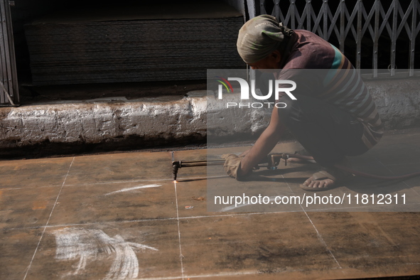 A laborer cuts an iron plate outside a shop at a steel and iron wholesale market in Kolkata, India, on November 26, 2024. In November 2024,...