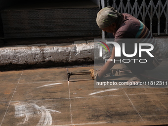 A laborer cuts an iron plate outside a shop at a steel and iron wholesale market in Kolkata, India, on November 26, 2024. In November 2024,...