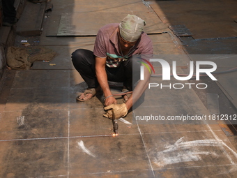 A laborer works with an iron plate outside a shop at a steel and iron wholesale market in Kolkata, India, on November 26, 2024. In November...