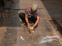 A laborer works with an iron plate outside a shop at a steel and iron wholesale market in Kolkata, India, on November 26, 2024. In November...