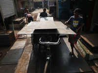 Labourers carry an iron plate to load onto a cycle rickshaw outside a shop at a steel and iron wholesale market in Kolkata, India, on Novemb...