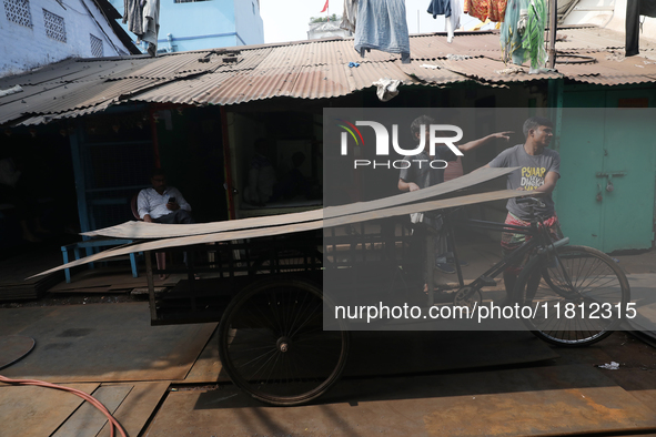 Labourers carry an iron plate to load onto a cycle rickshaw outside a shop at a steel and iron wholesale market in Kolkata, India, on Novemb...