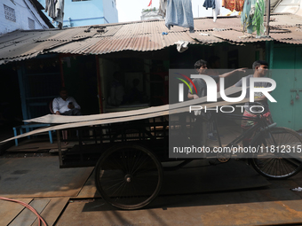 Labourers carry an iron plate to load onto a cycle rickshaw outside a shop at a steel and iron wholesale market in Kolkata, India, on Novemb...