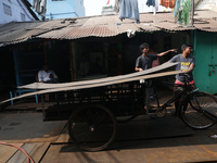 Labourers carry an iron plate to load onto a cycle rickshaw outside a shop at a steel and iron wholesale market in Kolkata, India, on Novemb...