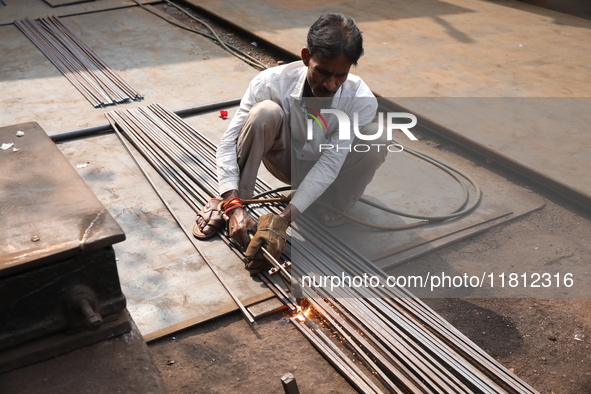 A laborer cuts iron rods outside a shop at a steel and iron wholesale market in Kolkata, India, on November 26, 2024. In November 2024, Indi...