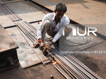 A laborer cuts iron rods outside a shop at a steel and iron wholesale market in Kolkata, India, on November 26, 2024. In November 2024, Indi...