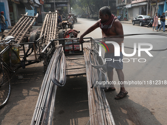 A laborer loads iron rods onto a cycle rickshaw outside a shop at a steel and iron wholesale market in Kolkata, India, on November 26, 2024....