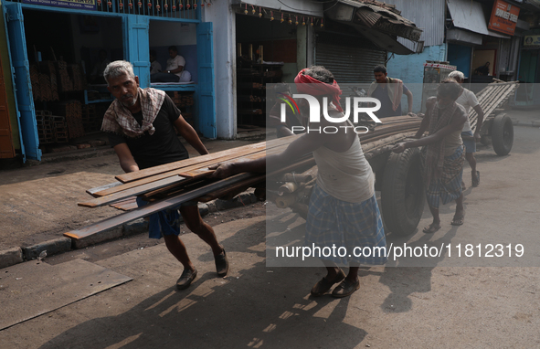 Labourers pull a handcart loaded with iron rods to a road construction site at a steel and iron wholesale market in Kolkata, India, on Novem...