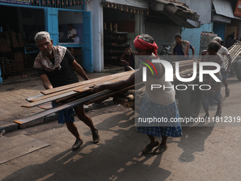 Labourers pull a handcart loaded with iron rods to a road construction site at a steel and iron wholesale market in Kolkata, India, on Novem...