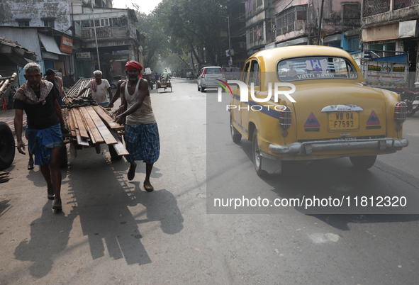 A laborer loads iron rods onto a cycle rickshaw outside a shop at a steel and iron wholesale market in Kolkata, India, on November 26, 2024....