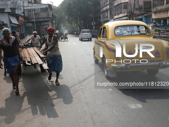 A laborer loads iron rods onto a cycle rickshaw outside a shop at a steel and iron wholesale market in Kolkata, India, on November 26, 2024....