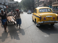 A laborer loads iron rods onto a cycle rickshaw outside a shop at a steel and iron wholesale market in Kolkata, India, on November 26, 2024....