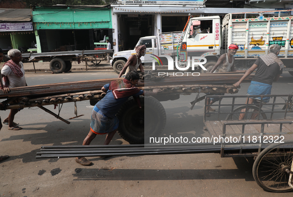 Labourers pull a handcart loaded with iron rods to a road construction site at a steel and iron wholesale market in Kolkata, India, on Novem...