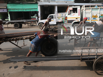 Labourers pull a handcart loaded with iron rods to a road construction site at a steel and iron wholesale market in Kolkata, India, on Novem...