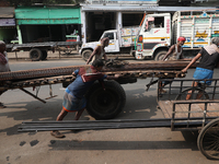 Labourers pull a handcart loaded with iron rods to a road construction site at a steel and iron wholesale market in Kolkata, India, on Novem...