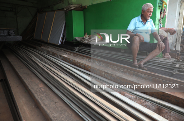 A trader sits inside his shop beside a dog at a wholesale steel and iron market in Kolkata, India, on November 26, 2024. In November 2024, I...