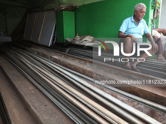 A trader sits inside his shop beside a dog at a wholesale steel and iron market in Kolkata, India, on November 26, 2024. In November 2024, I...