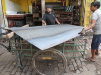 Labourers carry an iron plate to load onto a cycle rickshaw outside a shop at a steel and iron wholesale market in Kolkata, India, on Novemb...