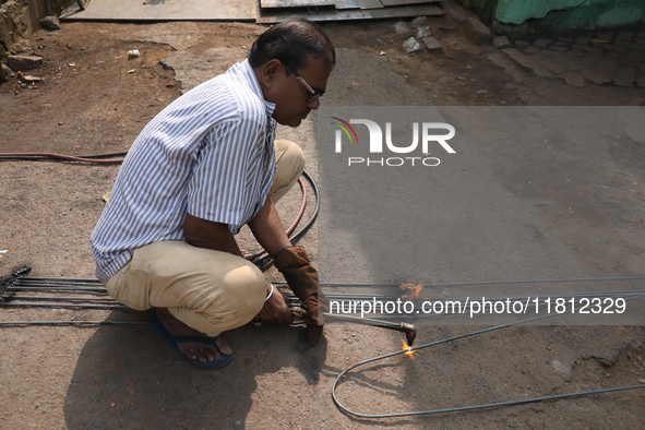 A laborer cuts an iron plate outside a shop at a steel and iron wholesale market in Kolkata, India, on November 26, 2024. In November 2024,...