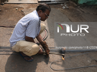 A laborer cuts an iron plate outside a shop at a steel and iron wholesale market in Kolkata, India, on November 26, 2024. In November 2024,...