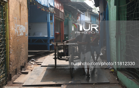 Labourers pull a cycle rickshaw loaded with iron plates at a wholesale iron market in Kolkata, India, on November 26, 2024. In November 2024...