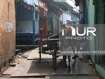 Labourers pull a cycle rickshaw loaded with iron plates at a wholesale iron market in Kolkata, India, on November 26, 2024. In November 2024...