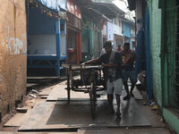 Labourers pull a cycle rickshaw loaded with iron plates at a wholesale iron market in Kolkata, India, on November 26, 2024. In November 2024...