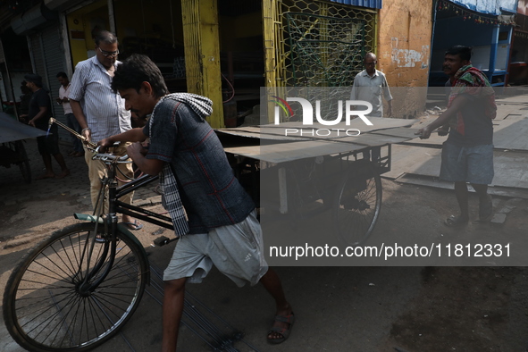 Labourers pull a cycle rickshaw loaded with iron plates at a wholesale iron market in Kolkata, India, on November 26, 2024. In November 2024...