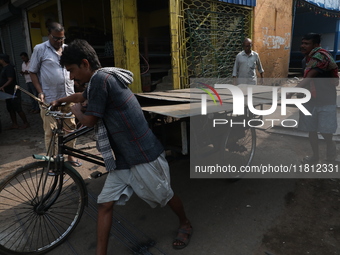 Labourers pull a cycle rickshaw loaded with iron plates at a wholesale iron market in Kolkata, India, on November 26, 2024. In November 2024...