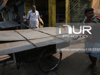 Labourers carry an iron plate to load onto a cycle rickshaw outside a shop at a steel and iron wholesale market in Kolkata, India, on Novemb...