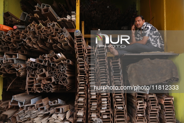 A trader speaks on his mobile phone inside his shop at a wholesale steel and iron market in Kolkata, India, on November 26, 2024. In Novembe...