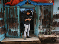 A trader looks at his mobile phone inside his shop at a wholesale steel and iron market in Kolkata, India, on November 26, 2024. In November...