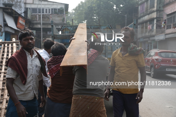 Labourers carry iron bars to load onto a truck at a steel and iron wholesale market in Kolkata, India, on November 26, 2024. In November 202...