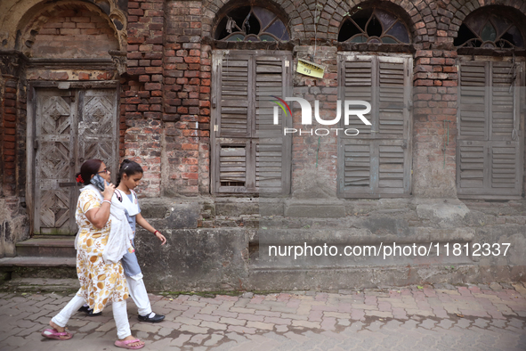 A woman speaks on her mobile phone as she walks past an abandoned temple near a steel and iron wholesale market in Kolkata, India, on Novemb...