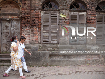 A woman speaks on her mobile phone as she walks past an abandoned temple near a steel and iron wholesale market in Kolkata, India, on Novemb...